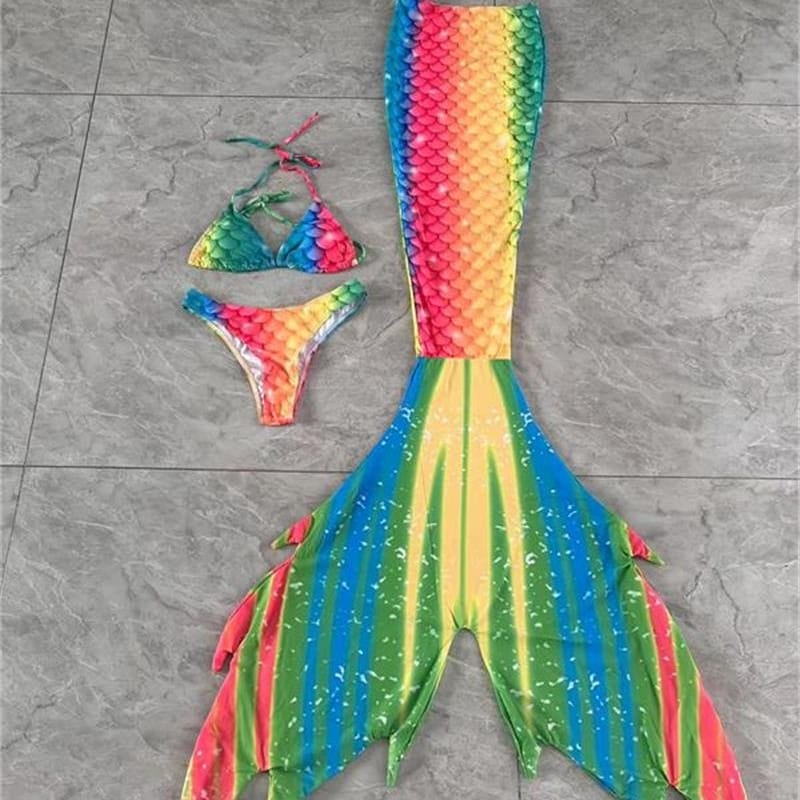 Adult woman swimming in crystal-clear hotel pool with shimmering swimmable mermaid tails, luxury aquatic experience
