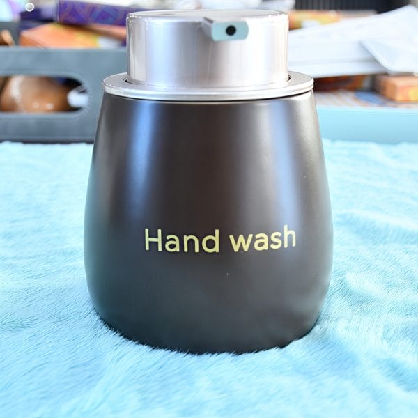 Ceramic soap dispenser with essential oil bottles, luxury spa bathroom.