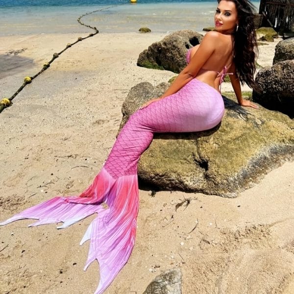 Guest swimming in turquoise lagoon with floral-print swimmable mermaid tail, luxury hospitality
