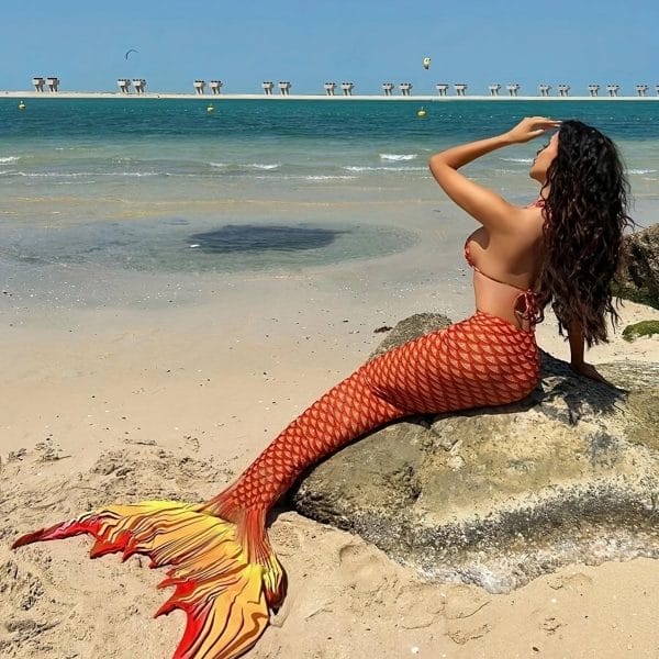 Dancers performing synchronized routine underwater with iridescent swimmable mermaid tails