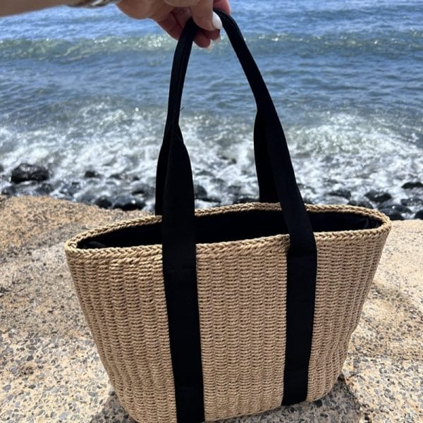 Zippered straw tote bag holding 15" laptop and cosmetic pouch, travel-friendly