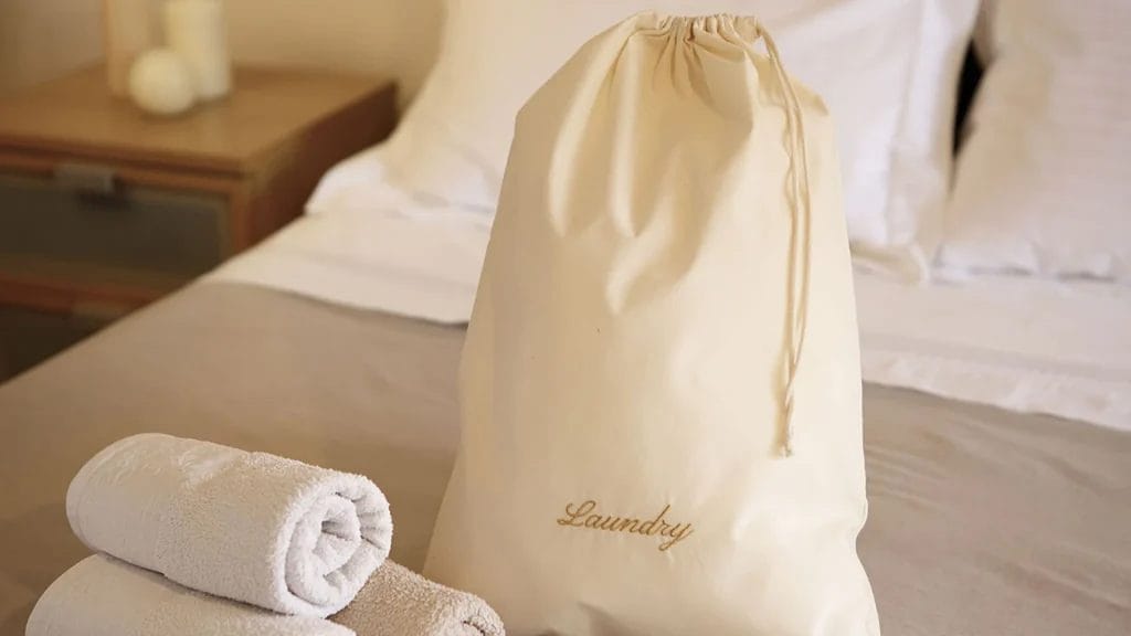 Large stack of various types of hotel laundry bags, showing bulk supply and consistent quality from DERBAL.