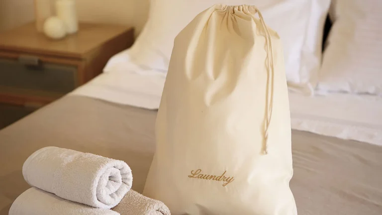 Large stack of various types of hotel laundry bags, showing bulk supply and consistent quality from DERBAL.