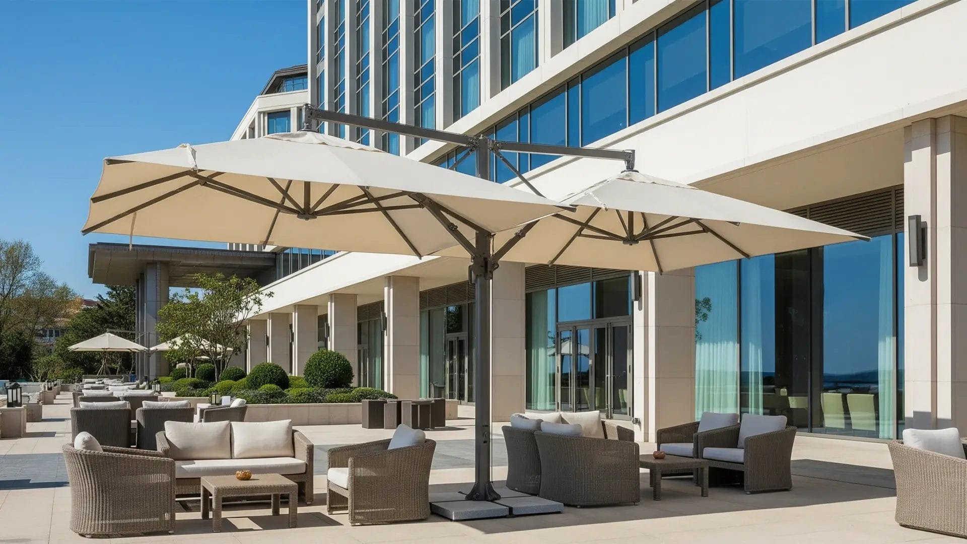A collection of DERBAL resort umbrellas in different sun umbrella sizes and styles, on a hotel patio or garden.