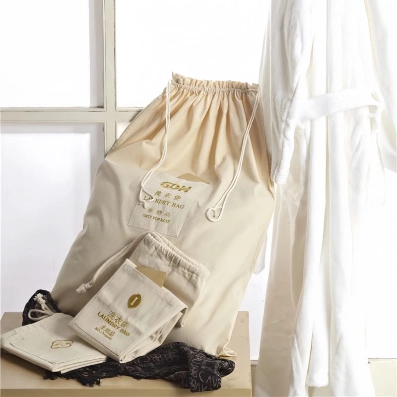 Stack of reusable organic cotton hotel laundry bags, emphasizing eco-friendly and sustainable materials.