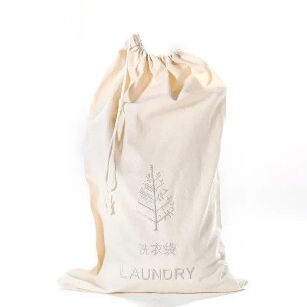 White non-woven hotel laundry bag with a convenient drawstring, placed neatly in a hotel guest room.