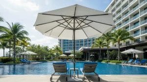 Guests relaxing on a shallow pool sun shelf under a specialized in pool umbrella, providing shade directly in the water.
