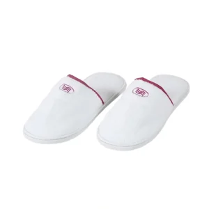 A pair of closed-toe Hotel Velour Slippers with an embroidered logo, symbolizing luxury hotel amenities.