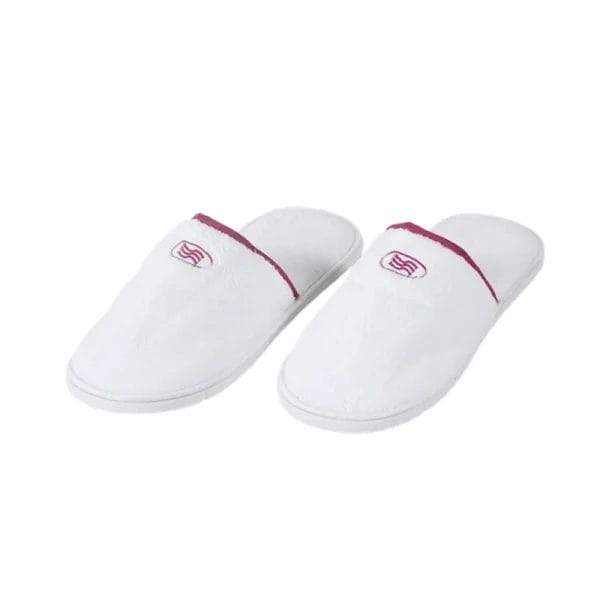 A pair of closed-toe Hotel Velour Slippers with an embroidered logo, symbolizing luxury hotel amenities.