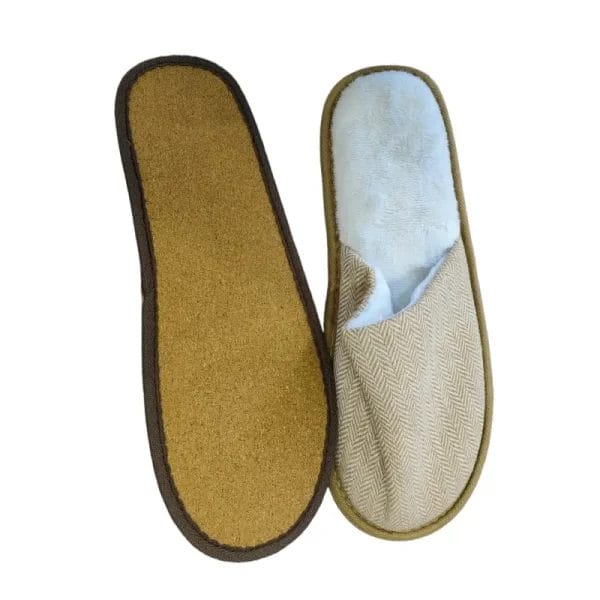 A close-up of a precisely embroidered luxury hotel logo on the natural fabric upper of a custom Hotel Eco-friendly Slipper.