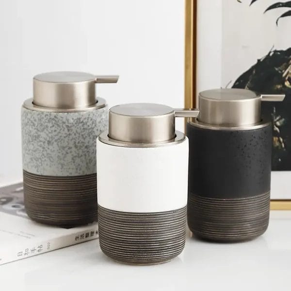 An elegant, embossed ceramic Foaming Soap Dispenser sitting on a marble bathroom countertop next to a modern sink, enhancing the luxurious hotel decor.