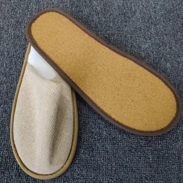 A welcoming scene in a luxury resort villa, with a pair of the Hotel Eco-friendly Slipper placed neatly on a natural wood floor beside a bed.