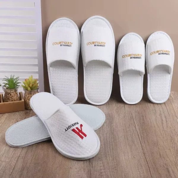 A single Waffle Slippers shown with other premium guest amenities like towels and robes, to highlight its role in a luxury experience.