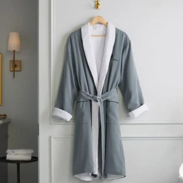 The modern slate grey version of the Luxury Hotel Bathrobe presented in a serene spa environment next to a bathtub, ready for a guest's use.