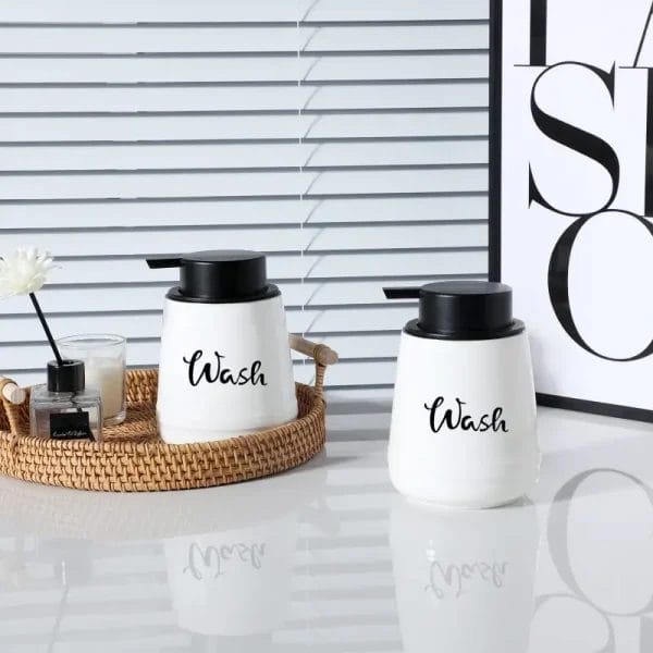 A set of elegant, clear Dispenser Bottles made of ceramic, neatly placed on a hotel bathroom vanity.