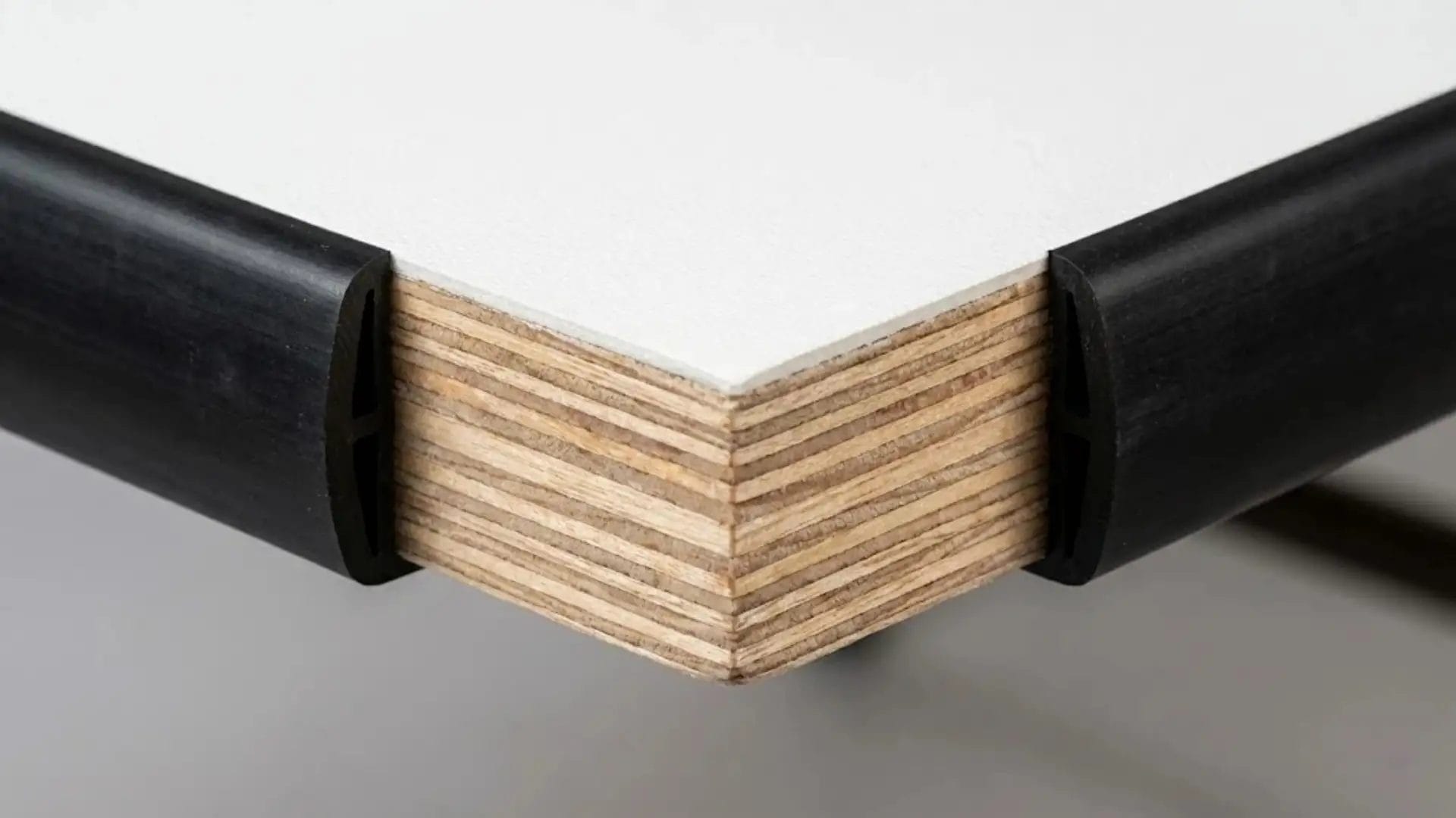 Close-up of 18mm heavy-duty plywood table top showing cross-grained wood layers and black PVC edge protection.