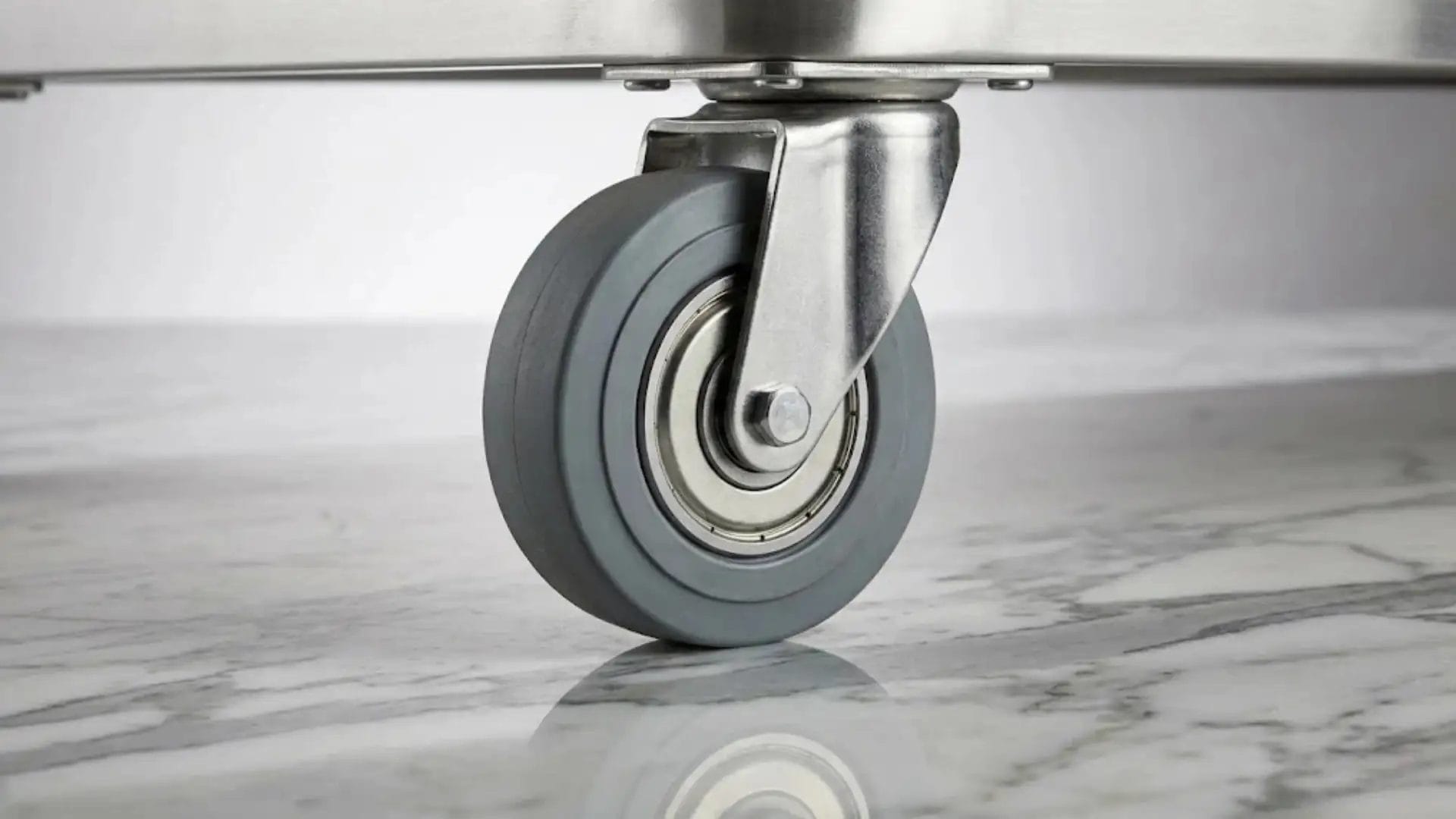 Macro detail shot of a heavy-duty non-marking PU caster wheel with sealed bearings on marble flooring.