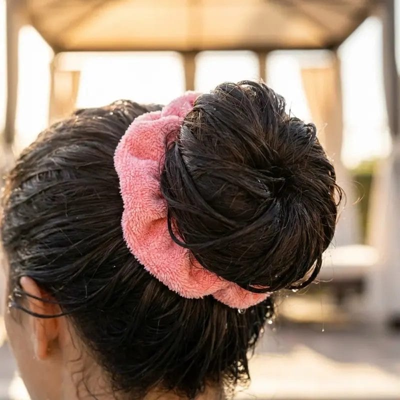 A woman using an absorbent quick-dry microfiber scrunchie to hold thick wet hair after swimming at a hotel pool.
