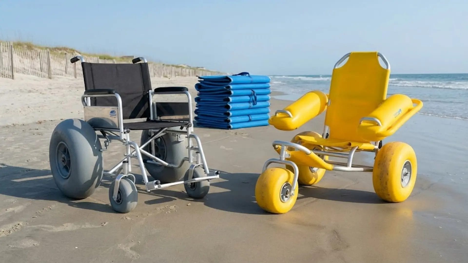 A balloon tire beach wheelchair and an amphibious model parked side-by-side on the sand.