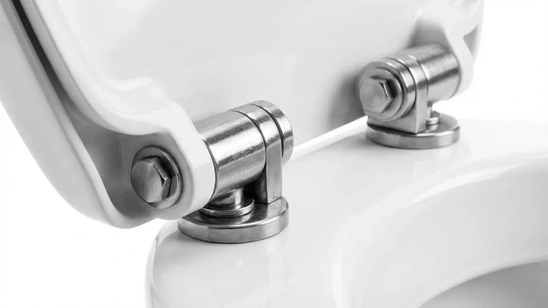 Close-up macro shot of heavy-duty stainless steel metal hinges on a commercial toilet seat.