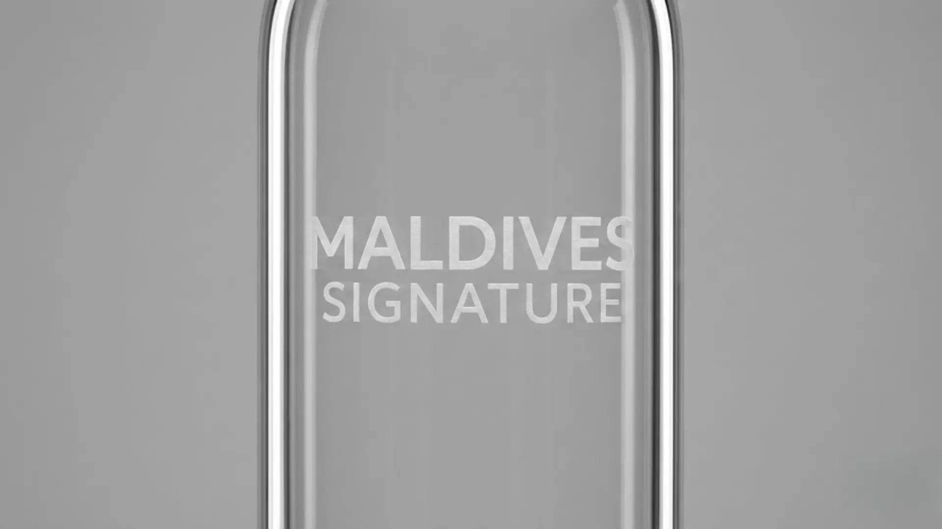 Macro shot of laser engraved MALDIVES SIGNATURE logo on a frosted glass surface.