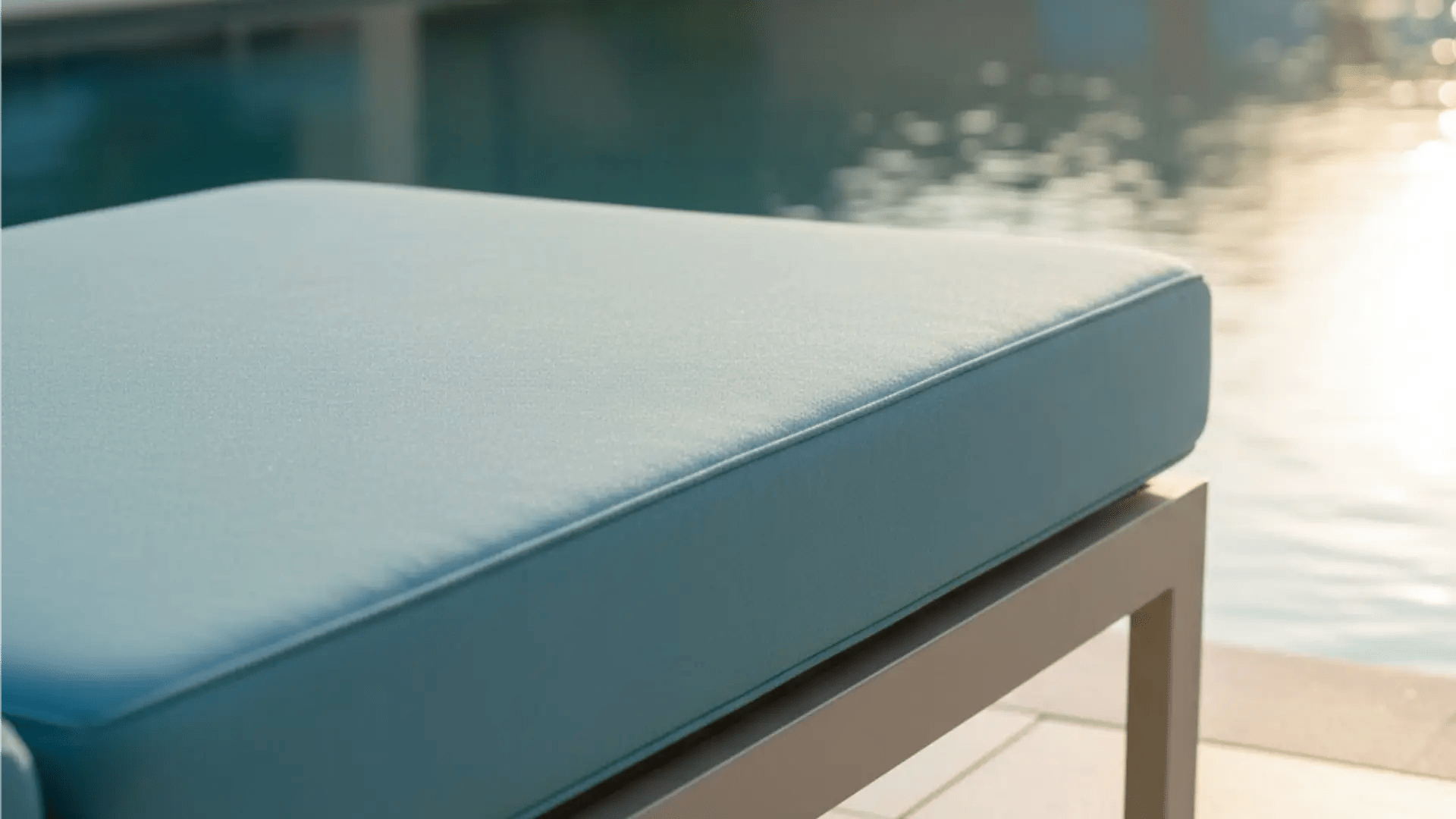 Close-up of a dry, light blue cushioned outdoor lounge chair on a resort patio, emphasizing cleanliness and comfort.