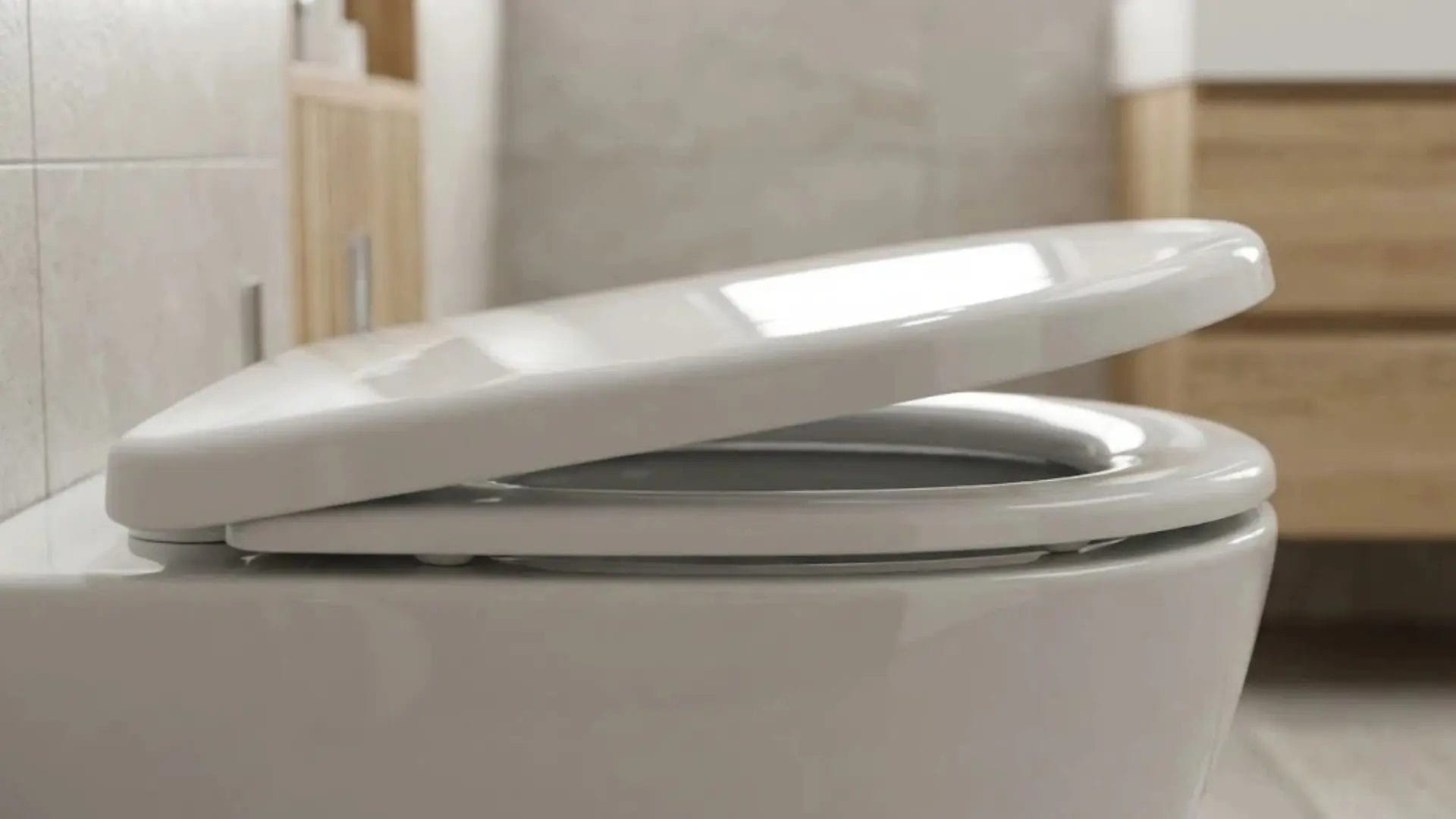 Side profile of a white UF resin toilet seat with soft-close mechanism closing gently.