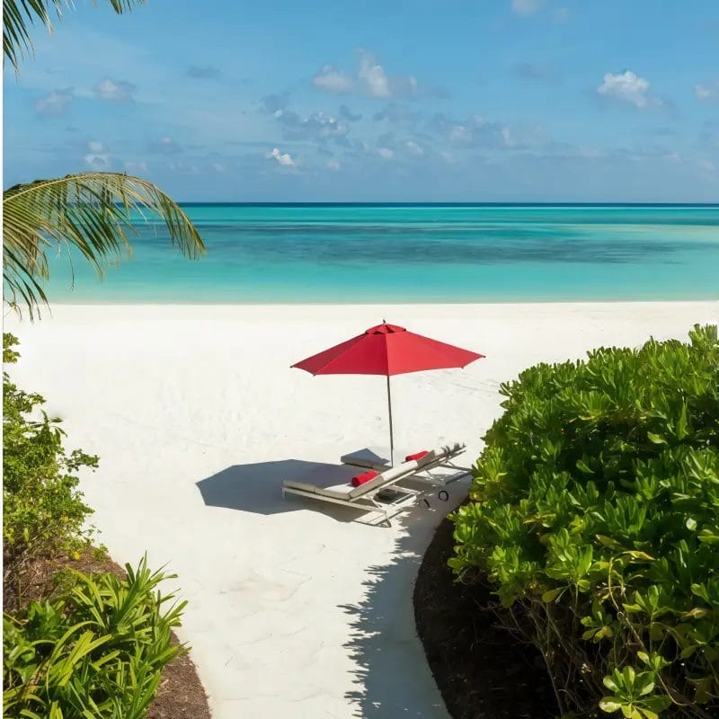 Commercial-grade red sun protection umbrella on a sandy beach with two sun loungers.