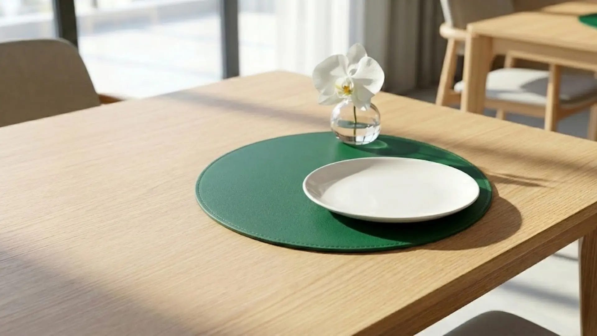 A modern round green leather table mat on a light wood table in a boutique hotel setting.