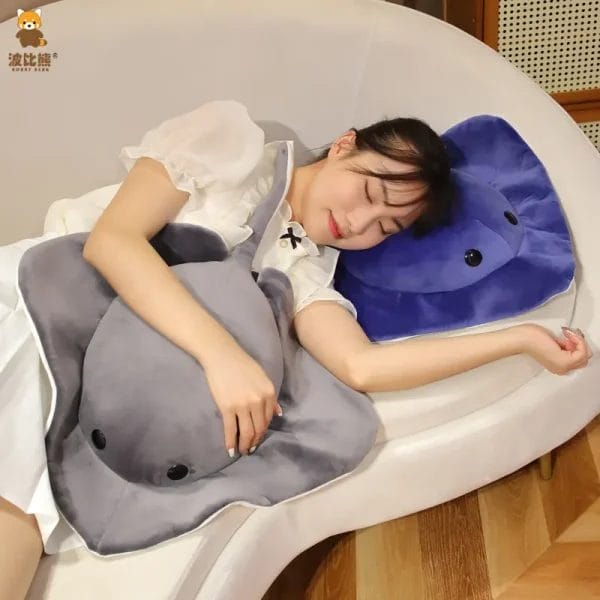 A high-quality blue and white plush manta ray toy resting elegantly on a luxury resort bed.